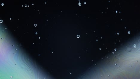beautiful dark liquid surface with white bubbles: macro abstract shot