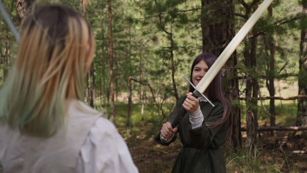 chica feliz con ropa medieval lucha con espadas en el bosque