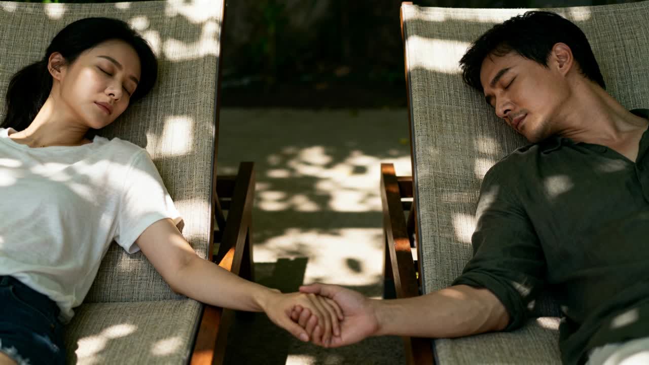 竖屏视频：一男一女斜躺着，双臂内伸，紧握双手，体现健康生活。