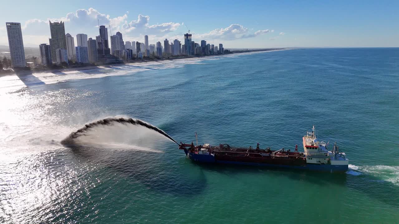 Drone captures a ship pumping sand off Gold Coast, Australia, with city skyline and ocean waves in the background