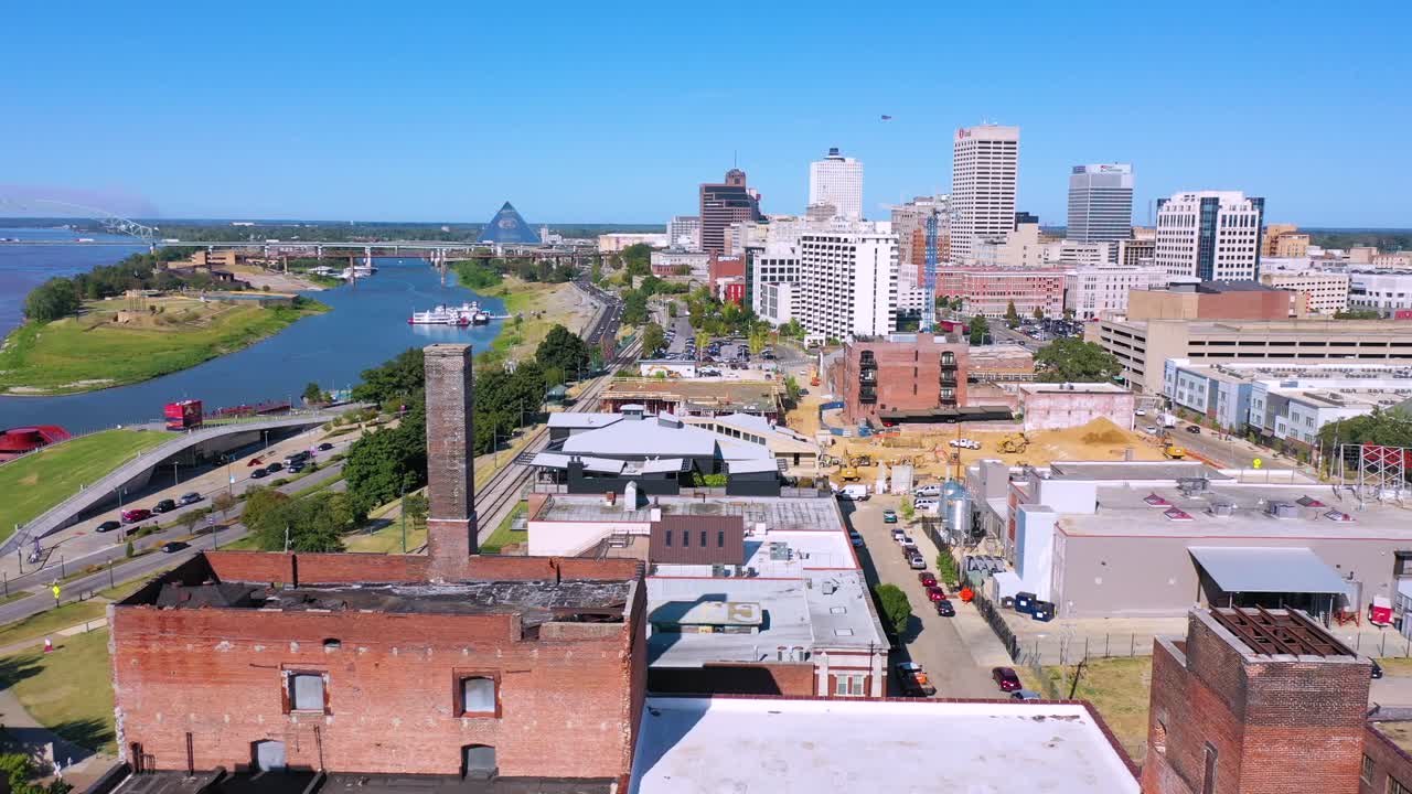 Aerial over Memphis Tennessee waterfront and Mud Island with Memphis pyramid background and old brick factories foreground