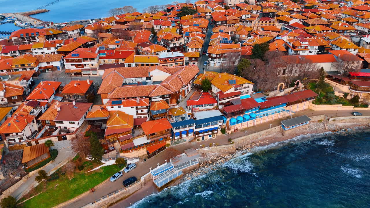 Ripresa con drone di case sul mare con tetti di tegole arancioni. Vista costiera che mostra edifici residenziali e ristoranti lungo la costa rocciosa di giorno.