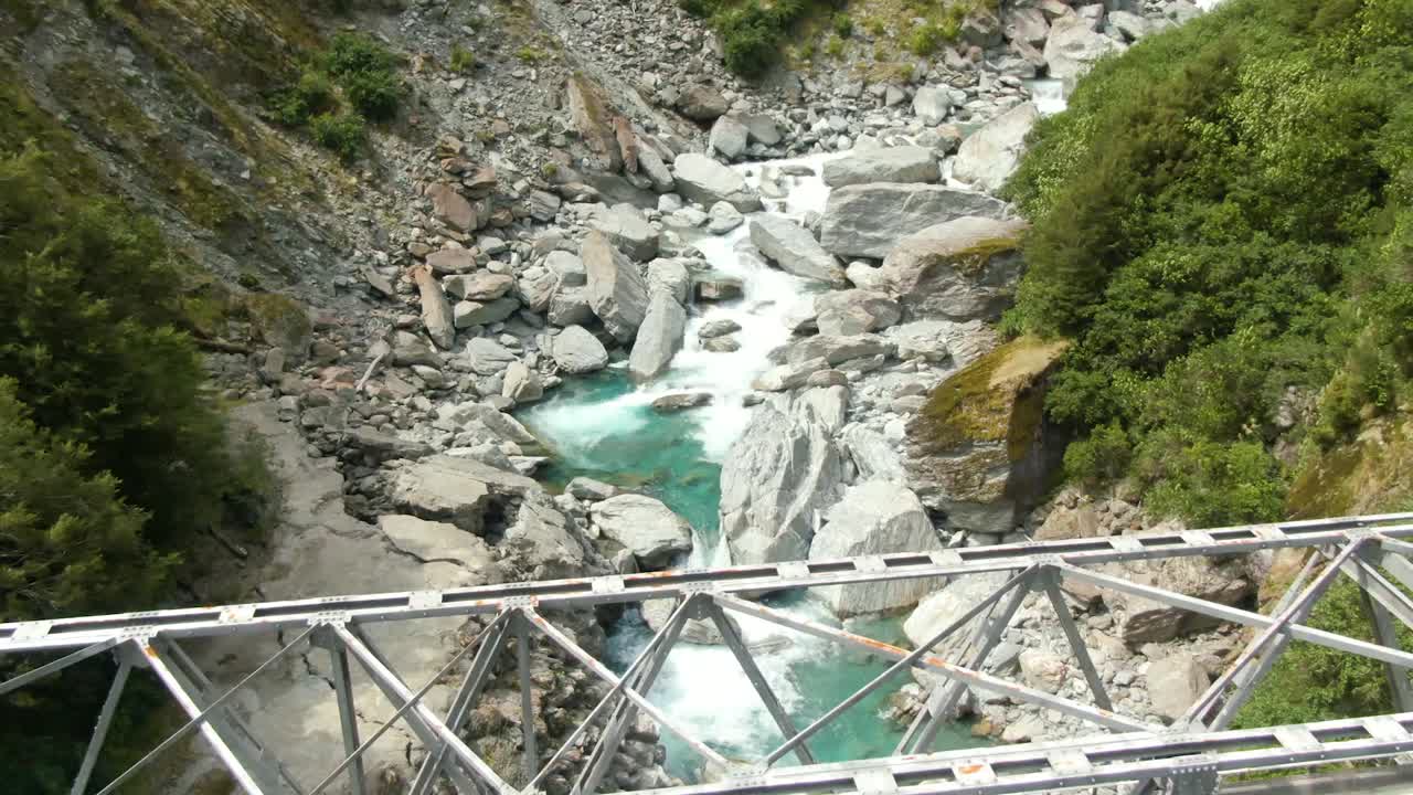 pequeño puente que cruza el flujo del río glacial azul rocoso