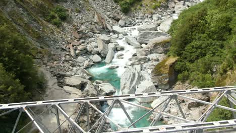 pequeño puente que cruza el flujo del río glacial azul rocoso