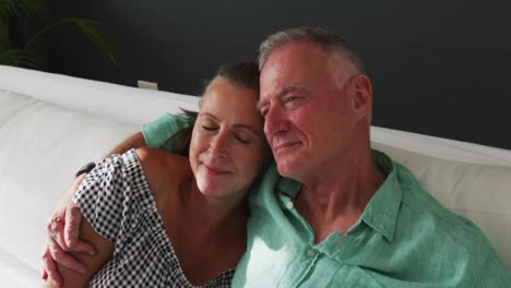 Caucasian-senior-couple-hugging-each-other-while-sitting-on-the-couch-at-home