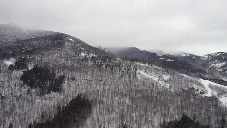 a slow rising drone shot with a dramatic low cloud ceiling shrouding the top of whiteface mountain in the adirondacks, upstate ny during midwinter.
