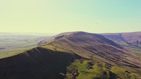 aerial view over paragliders flying and landing at mam tor, england