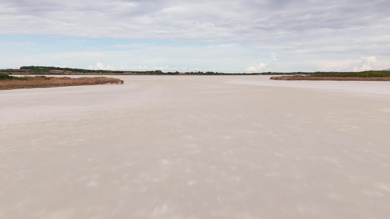 Aerial view of a vast saltwater lagoon in Sardinia, Italy. Surrounded by wild nature, this serene wetland is a haven for birdwatching and natural beauty, ideal for nature footage.