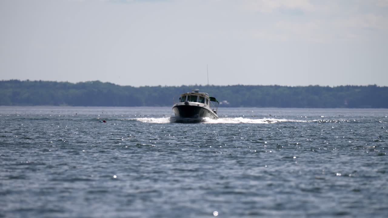 스피드 보트는 빛이 반이고 반이는 숲이 인 언덕을 배경으로 열린 물을 가로질러 미끄러집니다.