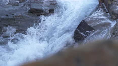 Syterbacken-Icy-small-stream-flowing-down-rocky-frozen-landscape-in-Lapland,-Sweden---Close-up