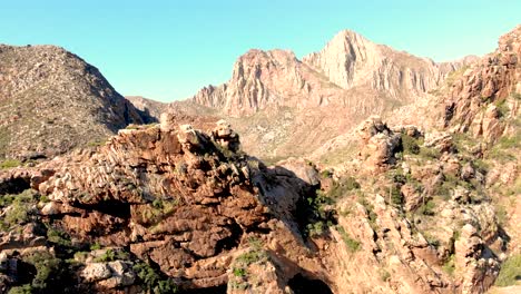 Una-Impresionante-Perspectiva-Desde-Un-Dron-Sigue-Un-Sinuoso-Camino-De-Montaña,-Ascendiendo-Para-Revelar-Una-Vista-Cautivadora-De-Infinitos-Picos-Y-Un-Extenso-Camino-Que-Conduce-Hacia-El-Horizonte-Distante