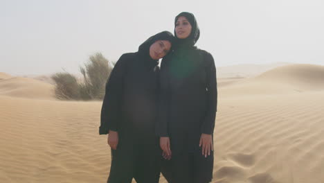 Porträt-Zweier-Muslimischer-Frauen-Im-Hijab,-Die-In-Einer-Windigen-Wüste-Stehen-1