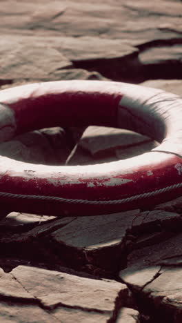 old red life preserver on rocky coastline