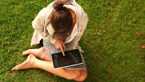 student working with tablet pc sitting on grass