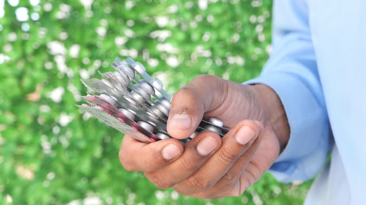 primer plano de una mano sosteniendo varios envases de pastillas