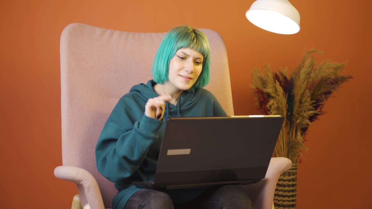 satisfecha con lo que ve en el portátil, la joven asiente con la cabeza.