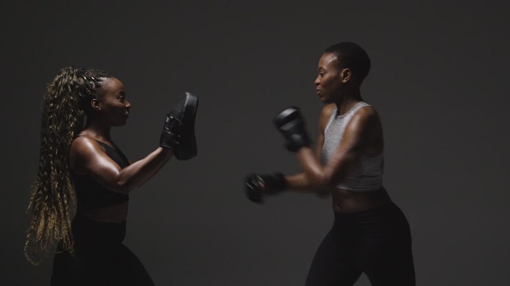 Studioaufnahme einer Frau mit Boxhandschuhen beim Sparring mit Trainer