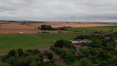 french countryside with fields, busy highway with truck and car traffic, landscape on cloudy day, france. aerial forward