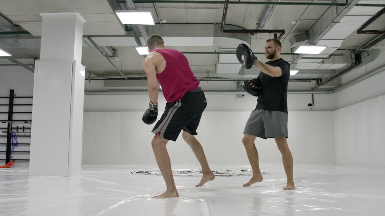 Coach and kick-boxers practice kicks in the jump with rotation on the paws in slow motion.