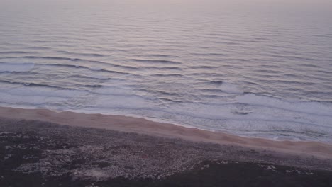 Praia-do-Norte-beach-Portugal-with-no-people-and-calm-sea-at-sunset,-aerial