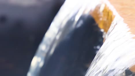 detailed view of water cascading smoothly over a wooden edge, showcasing fluid motion and texture.