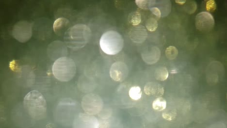 Schöne-Bokeh-Unschärfe,-Glitzernde-Staubpartikel-Im-Wasser,-Die-Sich-Bewegen,-Schöner-Hintergrund-Mit-Flackernden-Lichtaufnahmen