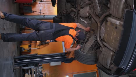 mechanic working under a lifted car in an auto repair shop