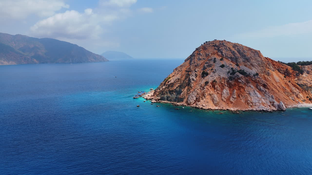 Scenic view of the Suluada Island in the Mediterranean Sea. Few boats stand at the bare rock. Turkey landmarks