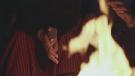 children sitting together and warming up hand near flame in cold weather