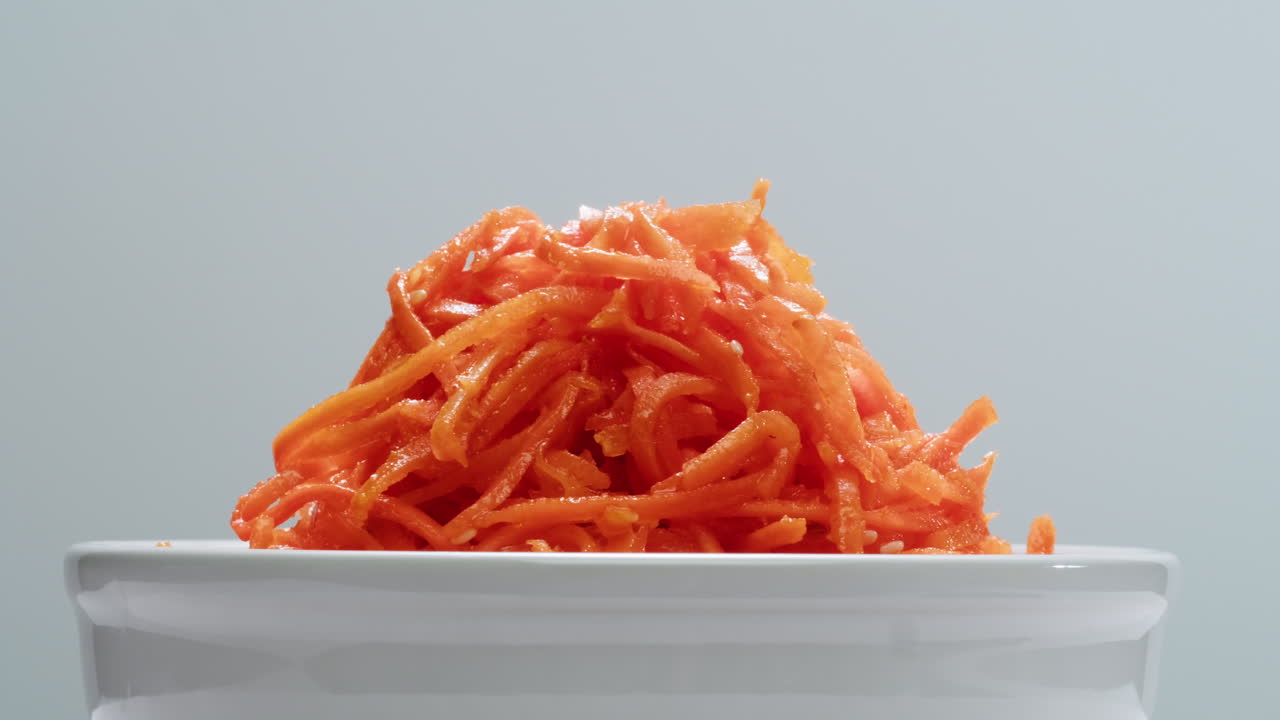 ensalada de zanahorias marinadas fermentadas, zanahorias picadas al estilo coreano, ajo, aceite vegetal y condimentos en una mesa giratoria