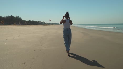 girl-wandering-around-at-the-beach,-waves-are-washing-up-shore-in-the-sunlight