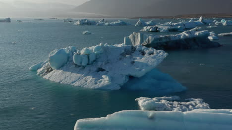 Hermosa-Vista-De-Drones-Paisaje-Frío-De-La-Laguna-Glaciar-Breidamerkurjokull-En-Islandia-Con-Icebergs-Flotantes.-Vista-Aérea-De-La-Laguna-Glaciar-Con-Bloques-De-Hielo-Derritiéndose-Y-Resquebrajándose-Del-Glaciar-Principal