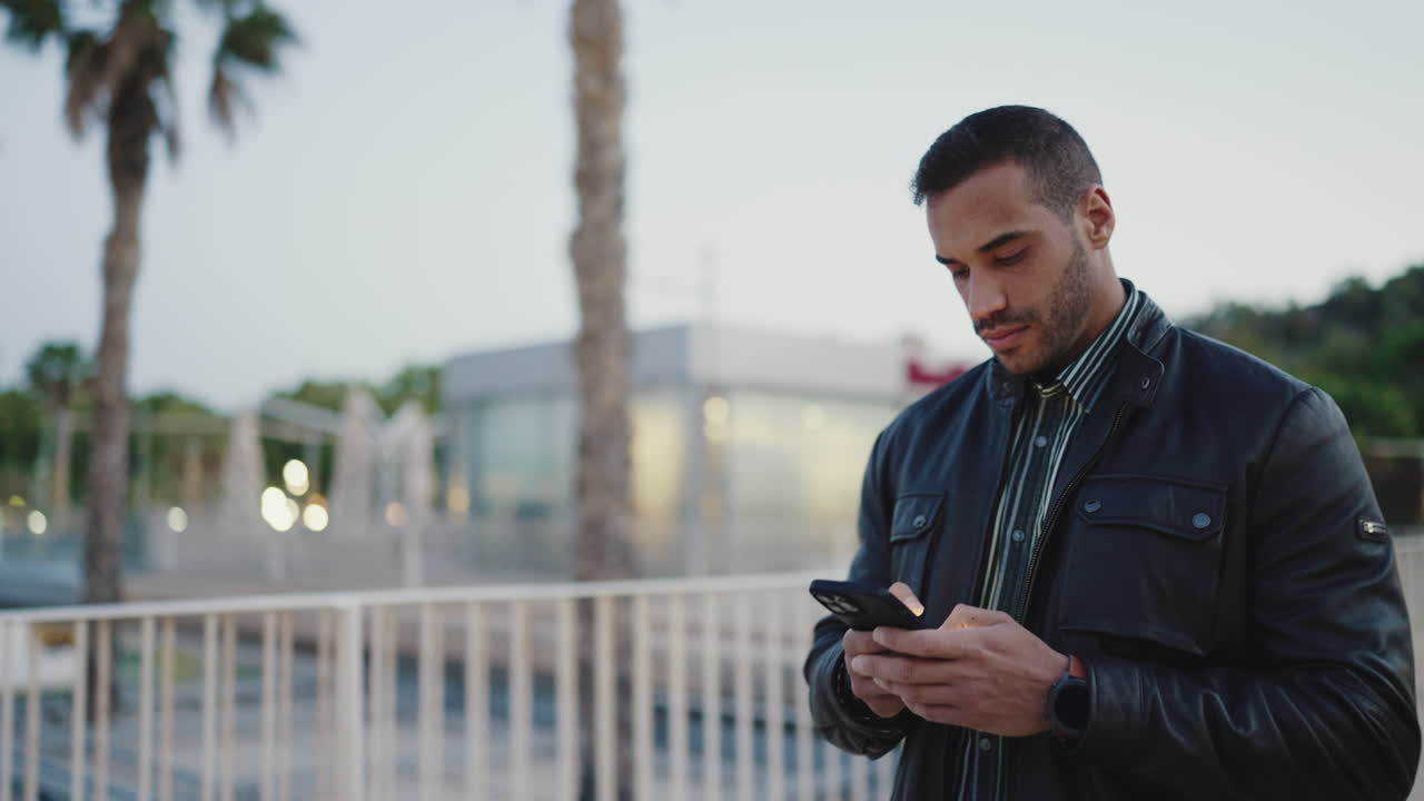 joven usando su teléfono inteligente y caminando al aire libre.
