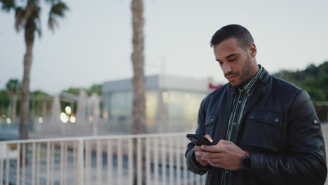 Young-man-using-smartphone-and-walking-outdoors.