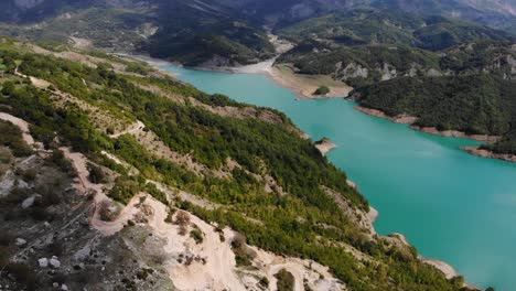 aerial flying towards turquoise waters of lake bovilla, abania