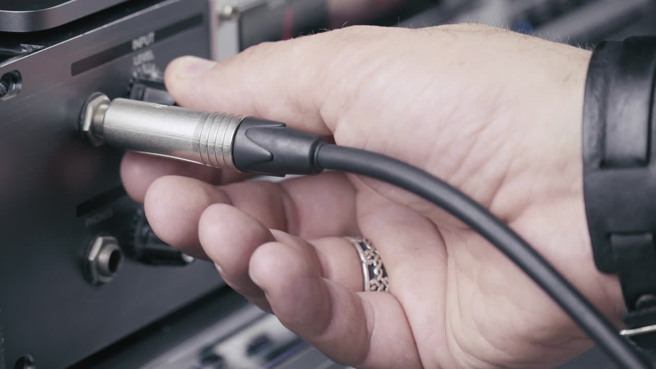 el músico conecta el cable jack a un multiefecto y configura el nivel de entrada al máximo, 4k