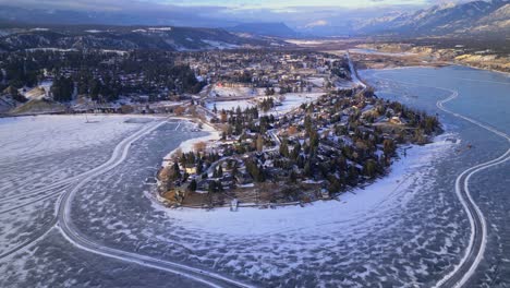 aerial drone view of windermere lake frozen over passing overhead of the city of windermere with ice skaters and manmade rinks made on the ice below