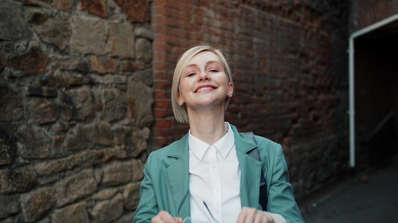Smiling woman in a teal blazer and sunglasses