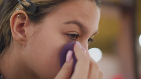 close-up shot of woman ensuring makeup is perfectly blended using beauty sponge. detailed view of smooth application, flawless complexion, and precise touch. soft lighting and blurred background