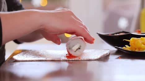 making sushi at home kitchen. woman hands rolling homemade sushi.