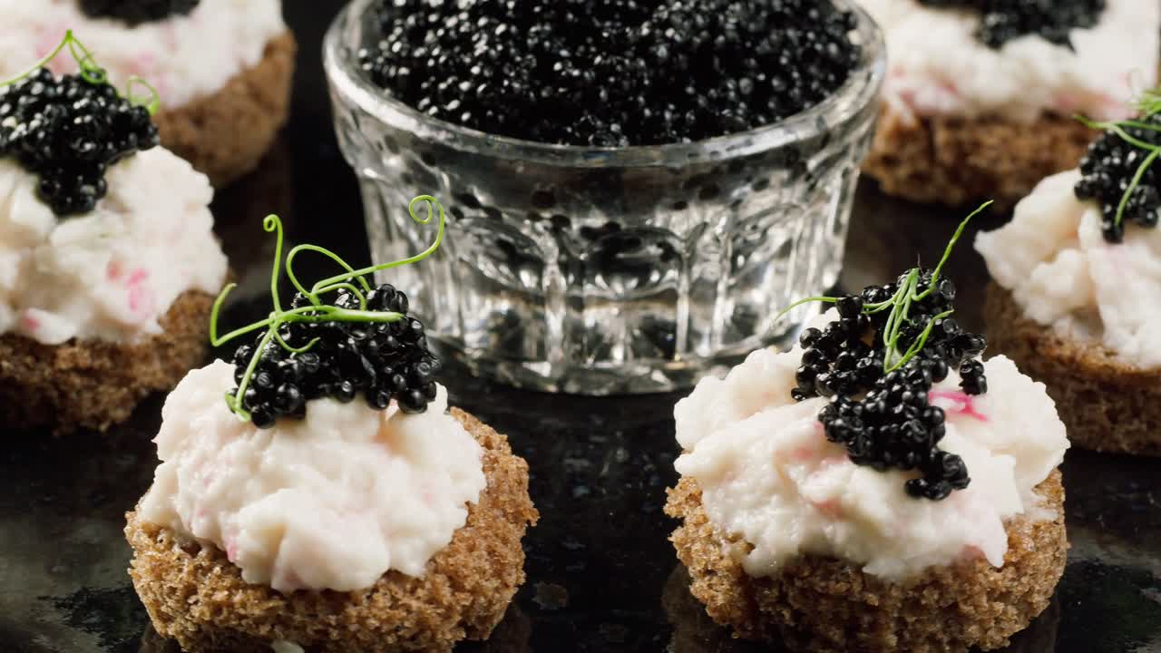 Élégants canapés au caviar noir avec une tartinade crémeuse et des micropousses