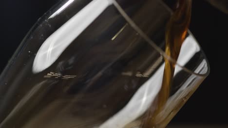 pint of irish stout being poured into glass against black studio background to celebrate st patricks day