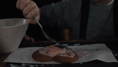 child decorating cookie with sugar sprinkles