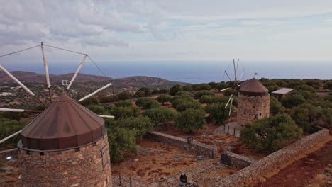 historic windmills overlook the sea on a scenic hillside in greece