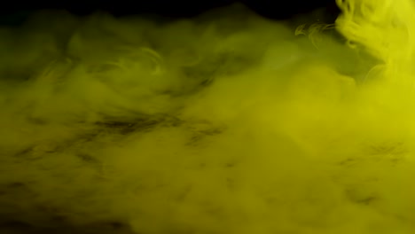yellow smoke dry ice on a black surface. closeup. slow motion