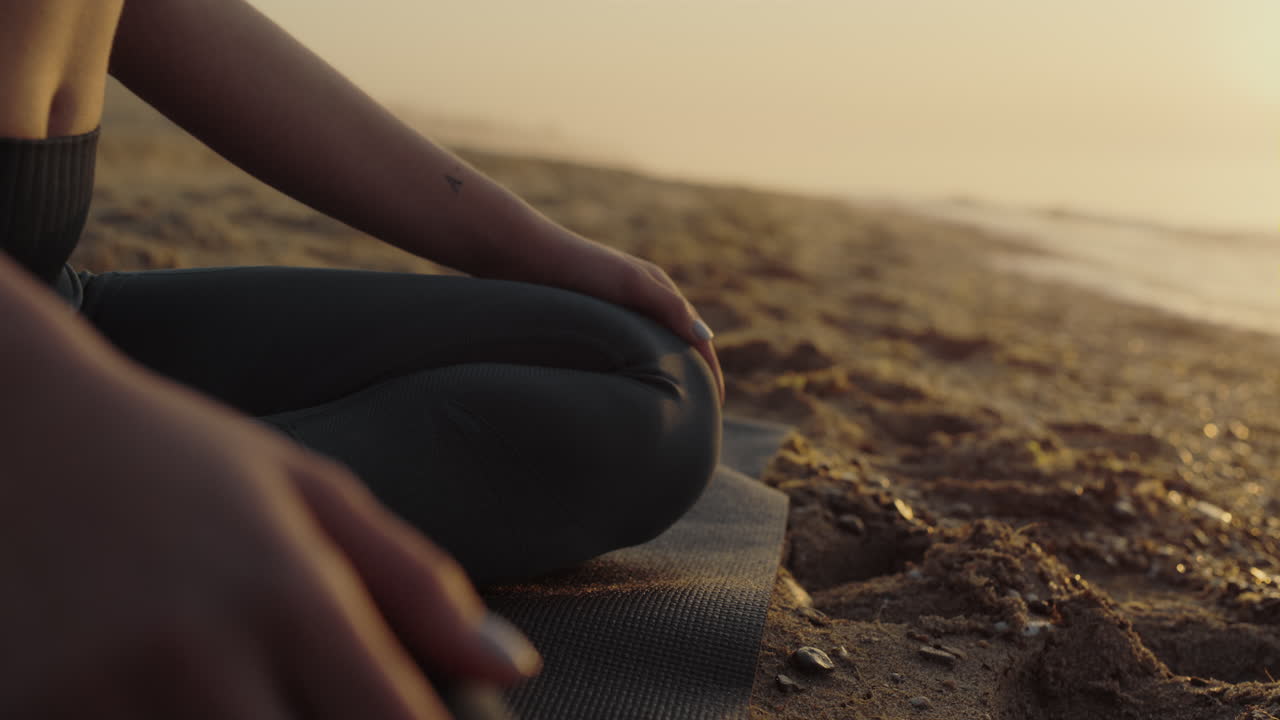 cuerpo de mujer sentada en pose de loto en una playa de arena de cerca. niña delgada meditando.