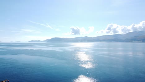 きらめく鮮やかな青い海と地平線の空撮を横切る風光明媚なスノードニア山脈