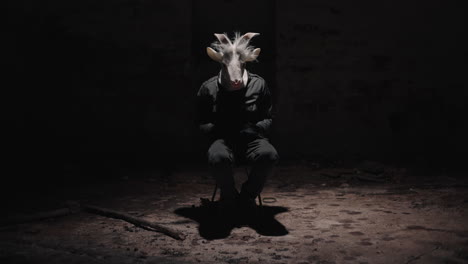 person with goat mask in dark room
