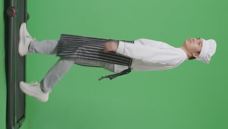 full body of side view asian man chef walking on treadmill and looking around in the green screen background studio