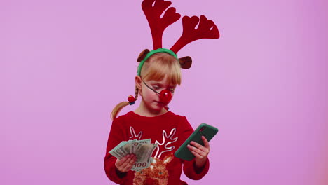 Girl-in-red-Christmas-deer-antlers-looking-smartphone-rejoicing-win-success-luck-receiving-money